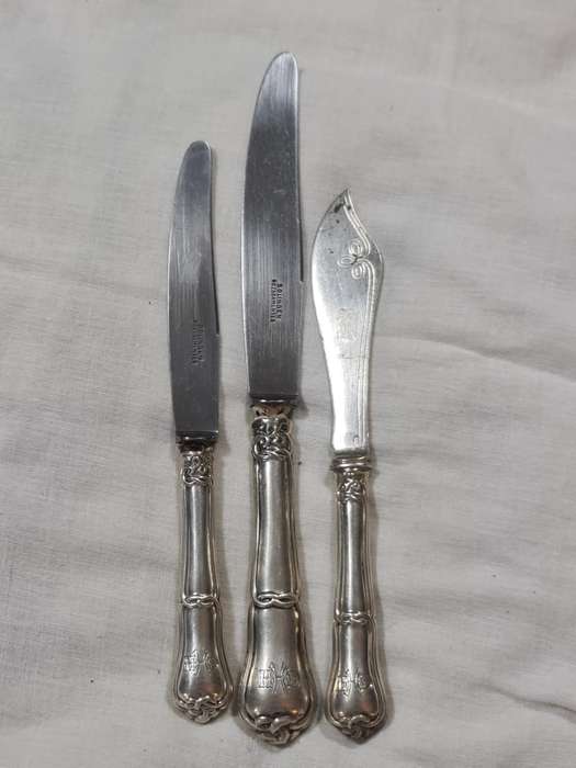 Three knifes with ornate handles and monogram on handle.
