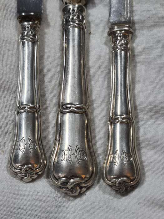 Three knifes with ornate handles and monogram on handle.