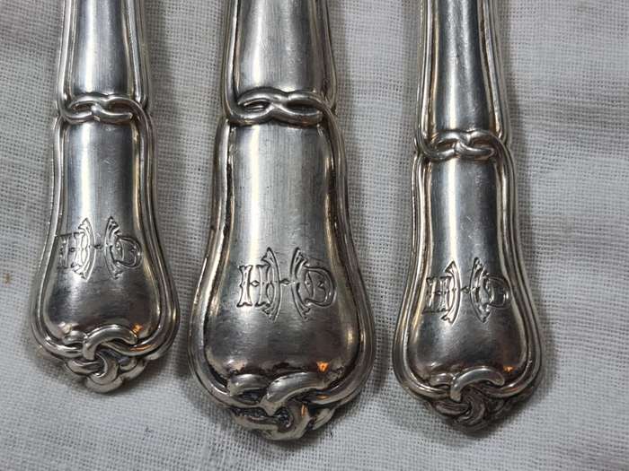 Three knifes with ornate handles and monogram on handle.