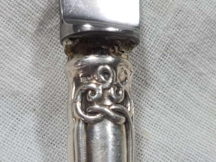 Three knifes with ornate handles and monogram on handle.