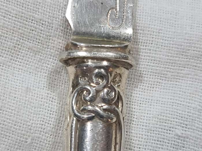 Three knifes with ornate handles and monogram on handle.