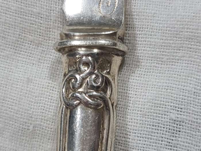 Three knifes with ornate handles and monogram on handle.