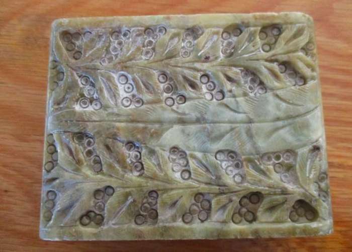 A vintage ornately carved stone trinket box with hinged lid