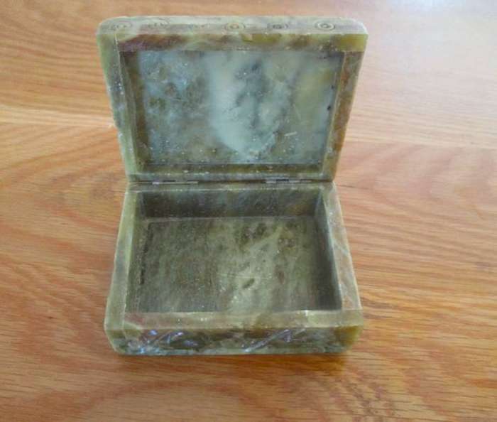 A vintage ornately carved stone trinket box with hinged lid