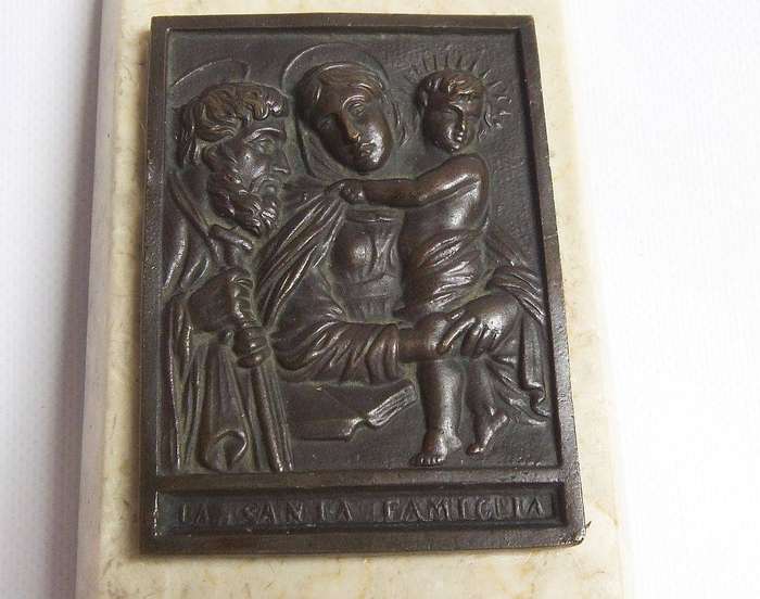 An old bronze plaque deskpiece depicting The Holy Family on an either marble or alabaster base