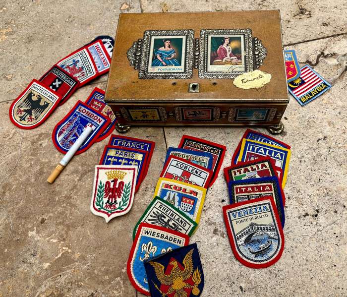 Stamp collector footed tin box with 25 travel badge lot Europe badges