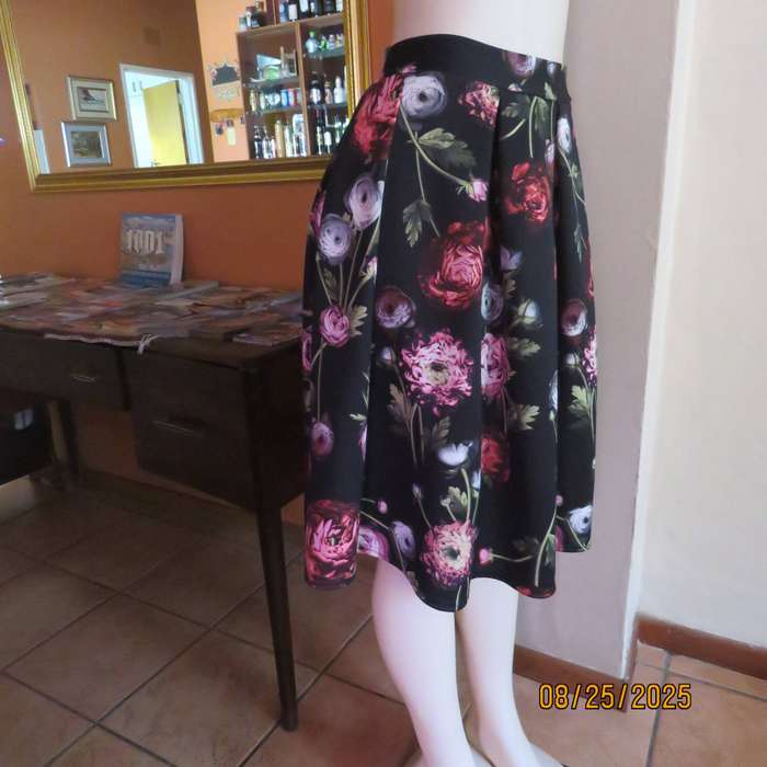 Black firm stretch polyester with red-pink floral print. With box pleats. Size 36