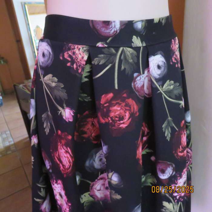 Black firm stretch polyester with red-pink floral print. With box pleats. Size 36