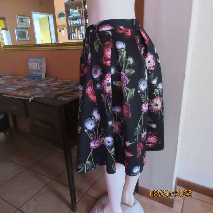 Black firm stretch polyester with red-pink floral print. With box pleats. Size 36