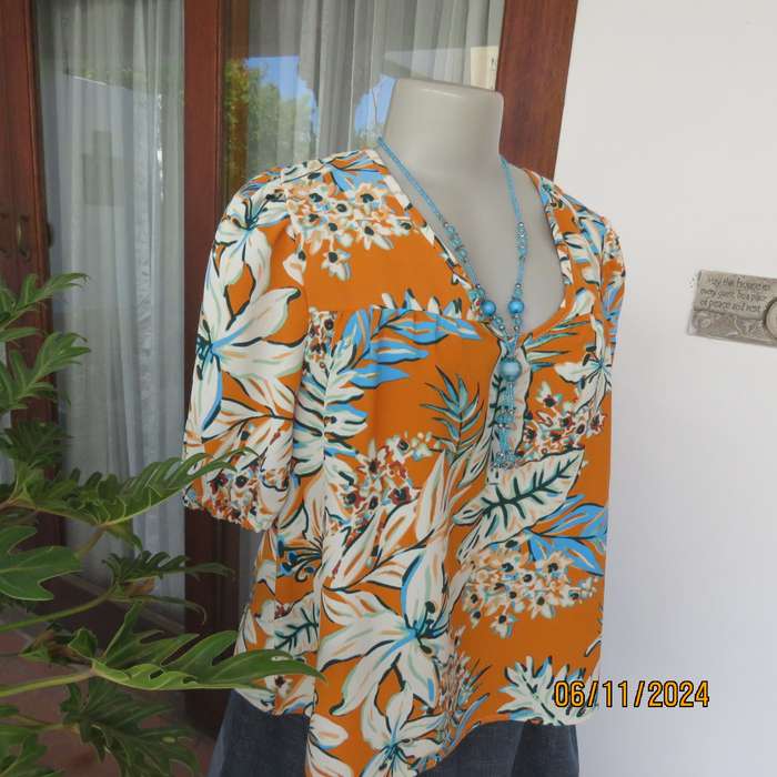 Eye catching slip over free hanging polyester top in burnt orange-blue and white flowers.Size 36.