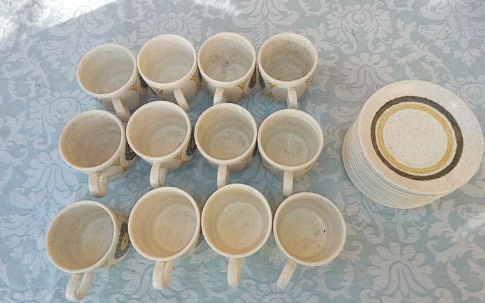 A VINTAGE STONEWARE SUNFLOWER DESIGN 24-PIECE TEACUP AND SAUCER SET