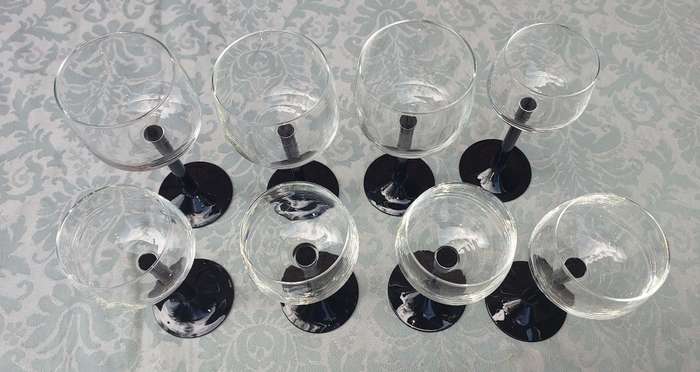 A SET OF 9 ART DECOR WINE GLASSES WITH BLACK STEMS SOLD AS IS
