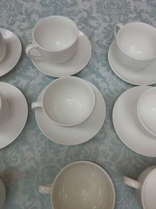 A COLLECTION OF 9 WHITE PORCELAIN TEACUPS AND 6 SAUCERS  SOLD AS IS