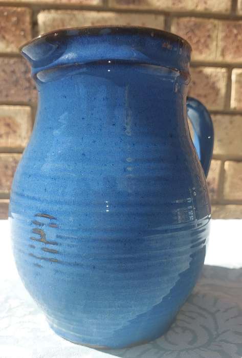 A VINTAGE CERAMIC BLUE GLAZED WATER JUG SOLD AS IS