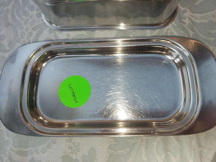 TWO STAINLESS STEEL UTENSILS A BUTTER DISH AND A TOAST STAND SOLD AS IS