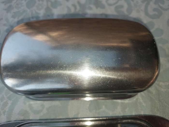 TWO STAINLESS STEEL UTENSILS A BUTTER DISH AND A TOAST STAND SOLD AS IS