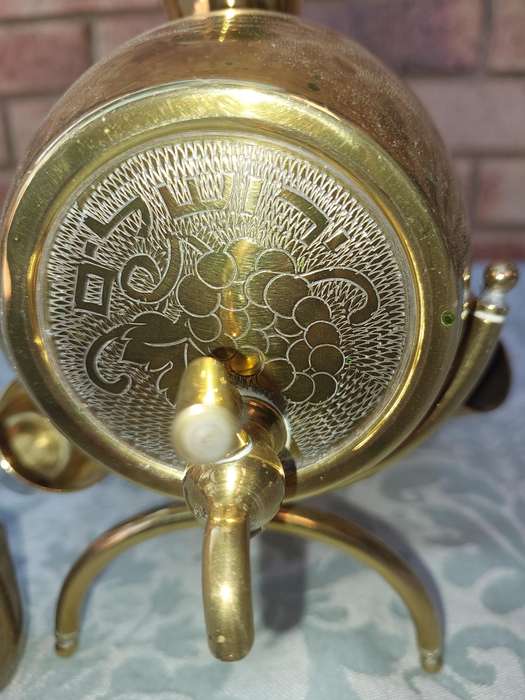 A VINTAGE HEBREW WINE DECANTER AND SIX CUPS BRASS ON A STAND ONE CUP NEED THE HANDLE TO BE ATTACHED