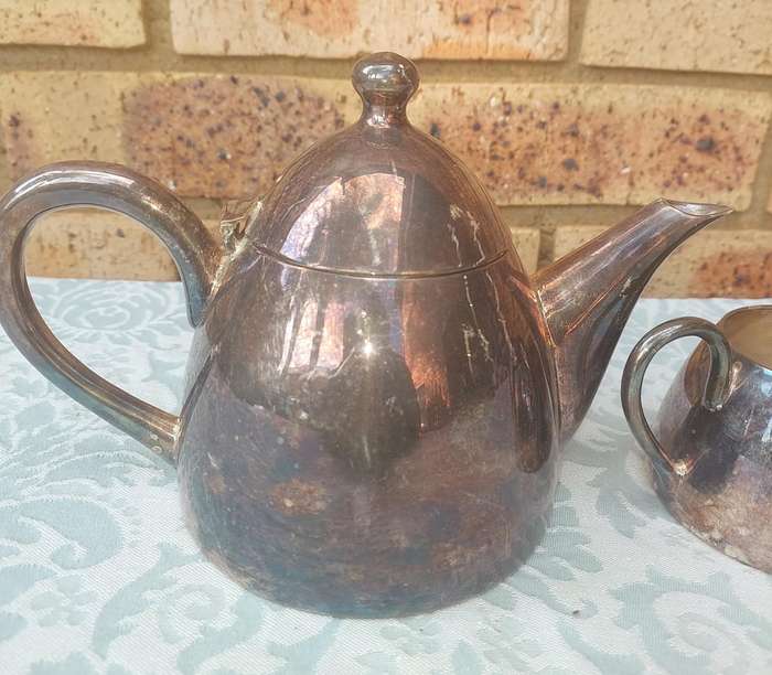 A VINTAGE SILVER PLATED TEAPOT WITH A MILK JUG AND A SUGAR BOWL SOLD AS IS