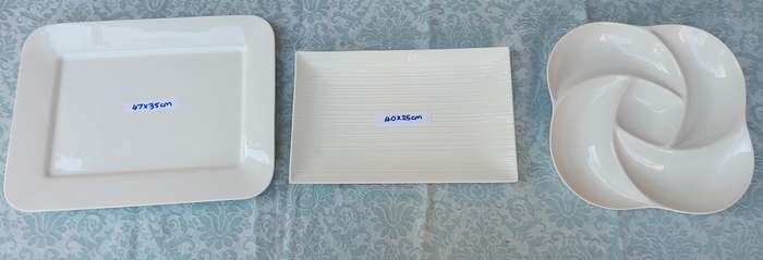A COLLECTION OF WHITE PORCELAIN PLATTERS SOLD AS IS
