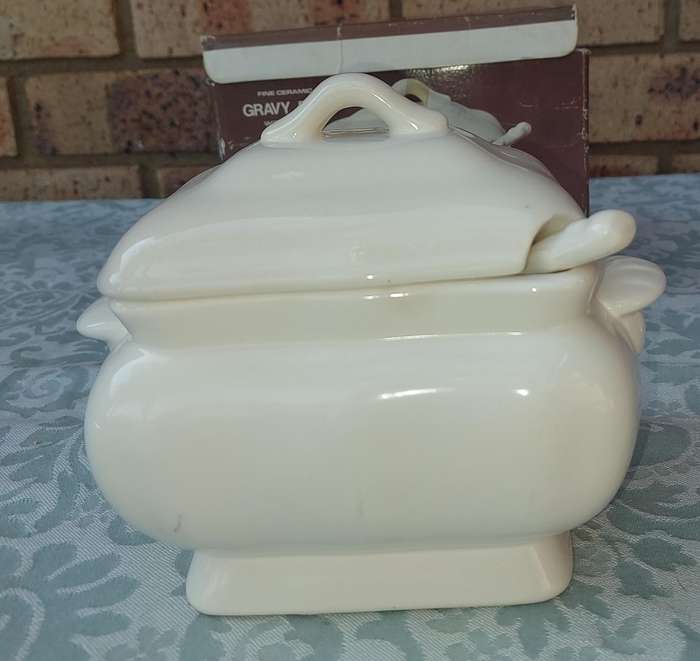 A WHITE CERAMIC GRAVY POT WITH A LADLE