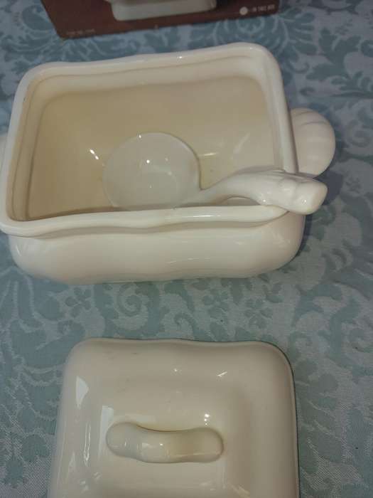 A WHITE CERAMIC GRAVY POT WITH A LADLE