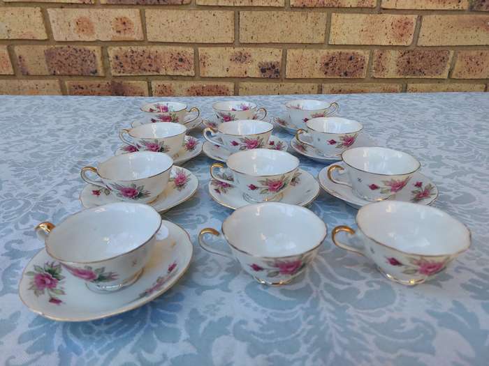 A SET OF 10 TEACUPS AND SAUCERS FINE ROSES WITH GOLD TRIM AND TWO EXTRA CUPS SOLD AS IS