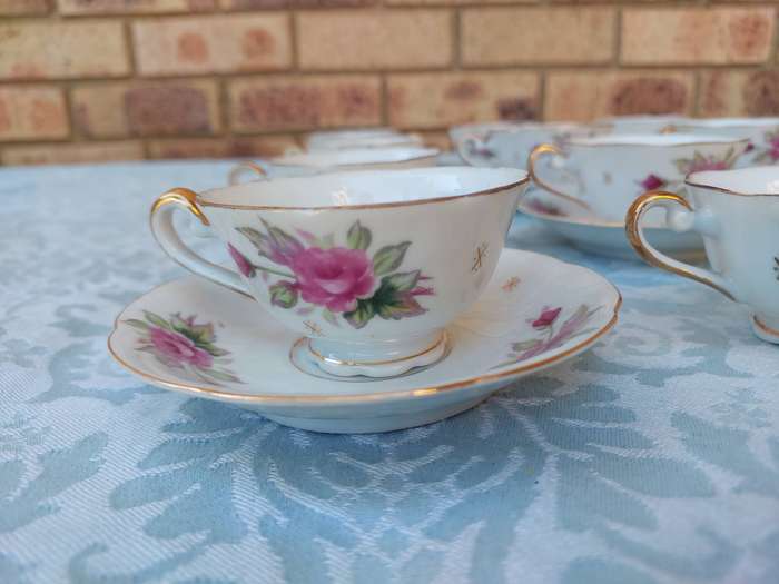 A SET OF 10 TEACUPS AND SAUCERS FINE ROSES WITH GOLD TRIM AND TWO EXTRA CUPS SOLD AS IS