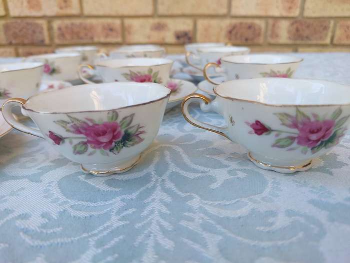 A SET OF 10 TEACUPS AND SAUCERS FINE ROSES WITH GOLD TRIM AND TWO EXTRA CUPS SOLD AS IS