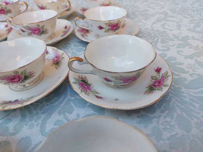 A SET OF 10 TEACUPS AND SAUCERS FINE ROSES WITH GOLD TRIM AND TWO EXTRA CUPS SOLD AS IS