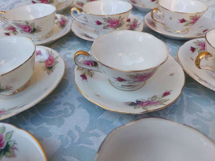 A SET OF 10 TEACUPS AND SAUCERS FINE ROSES WITH GOLD TRIM AND TWO EXTRA CUPS SOLD AS IS