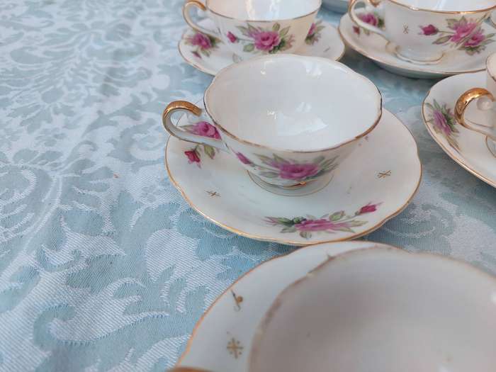 A SET OF 10 TEACUPS AND SAUCERS FINE ROSES WITH GOLD TRIM AND TWO EXTRA CUPS SOLD AS IS