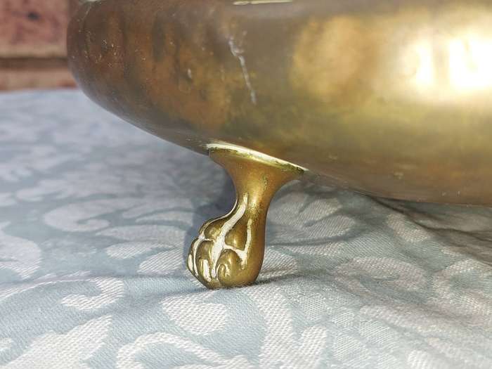 AN ORNATE VINTAGE BRASS SERVING BOWL WITH BALL AND CLAW LEGS SOLD AS IS