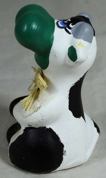 Ceramic cow seated with green nose