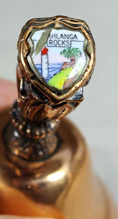 Souvenir copper bell - Umhlanga rock with lion topped figure embossed to shield