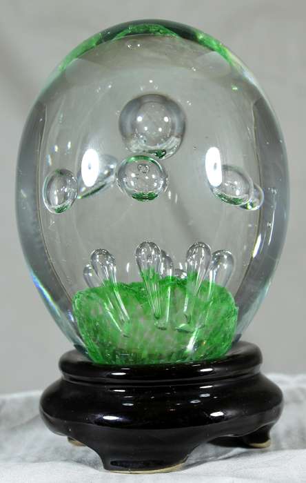 Glass paperweight with bubbles on green base on stand