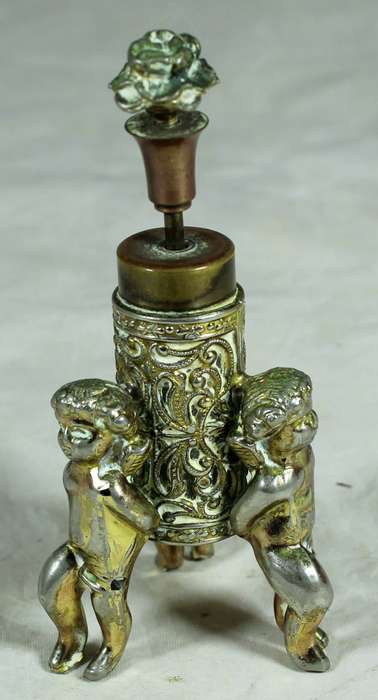 Small brass cherubs holding a perfume bottle