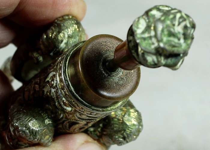 Small brass cherubs holding a perfume bottle