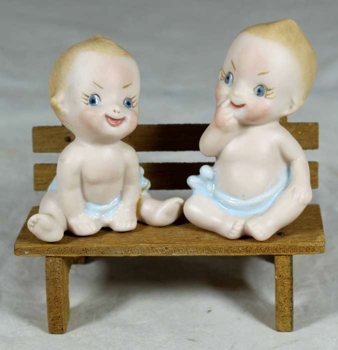 Two ceramic babies on a wooden bench
