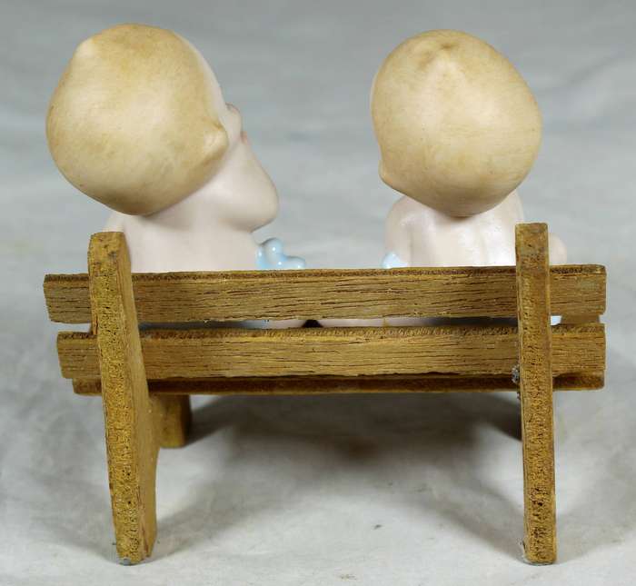 Two ceramic babies on a wooden bench
