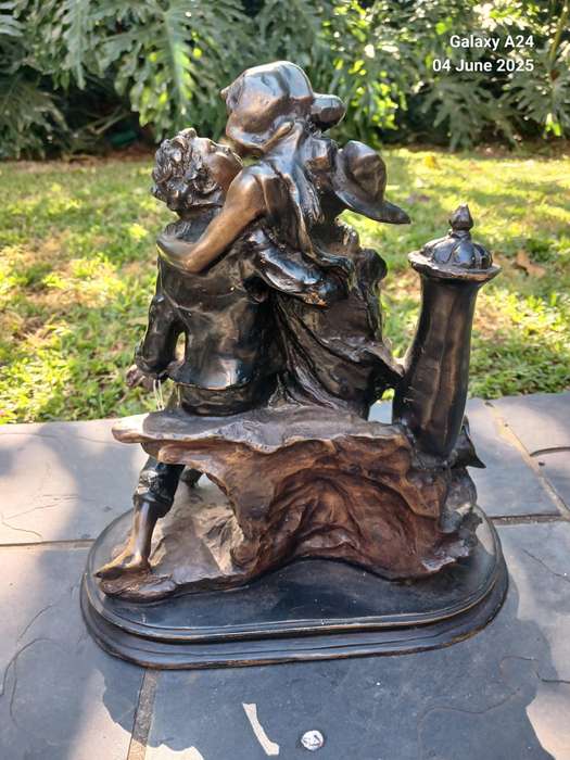 Bronze figurine of a seated boy and girl kissing
