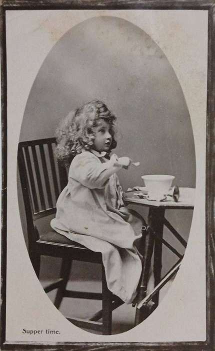 Vintage RPPC postcard of a Victorian era child eating dinner