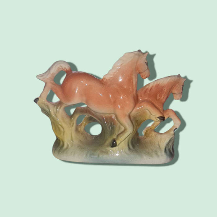 A vintage china-made pair of stylized horses finished in a playful pink and green speckled glossy gl