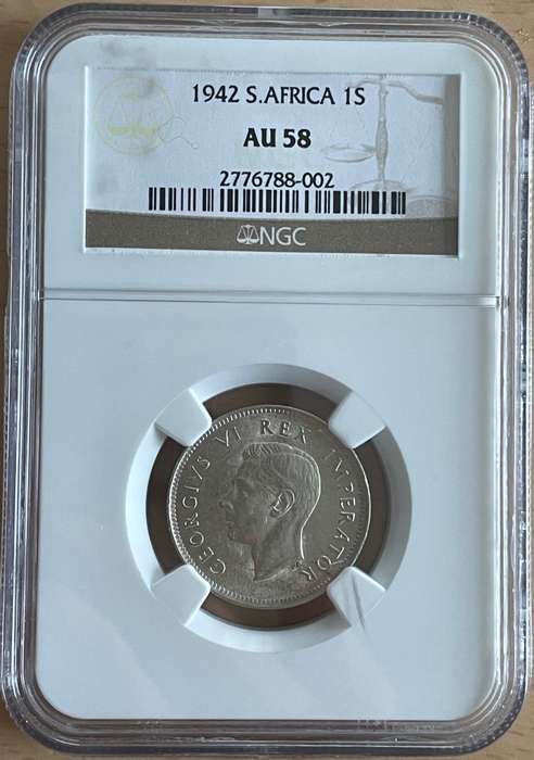 1942 SA shilling NGC AU 58. Rare multiple errors. A long cracked die and a cud flaw (extra metal)