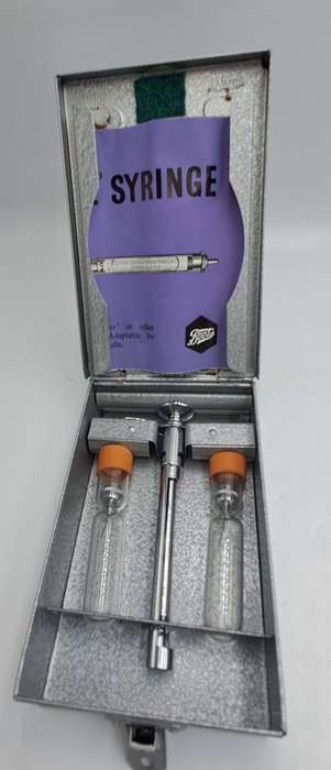 Boots viule syringe in a metal case with two glass containers with needles inside.