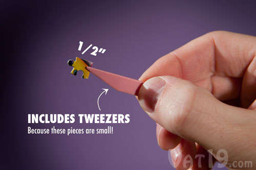 A piece from the World's Smallest Jigsaw Puzzle being held by a pair of tweezers.