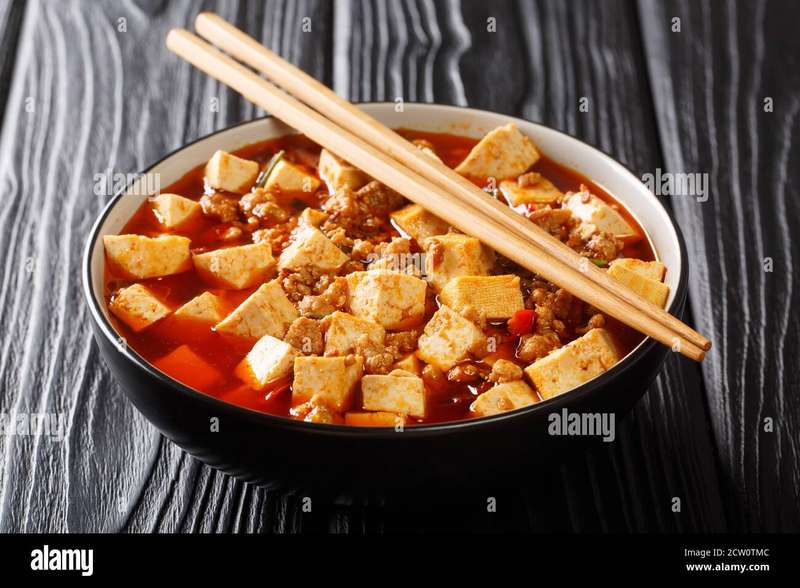 Chinese Mapo Tofu is fried Sichuan pork and tofu in a hot sauce close-up in a bowl on the table. horizontal Stock Photo - Alamy