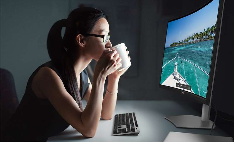 Woman with a cup in her hands and lips looking at a Dell S3221QSA Curved Monitor.