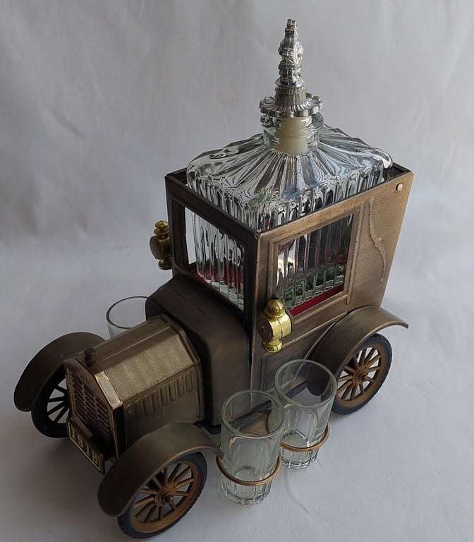 A Vintage 1970's, (1918 Model T Ford - Whisky Decanter) with a working musical box & shot glasses