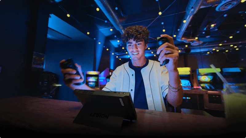 Young man sitting in front of a Legion Go in Detachable Mode, using the detachable controllers