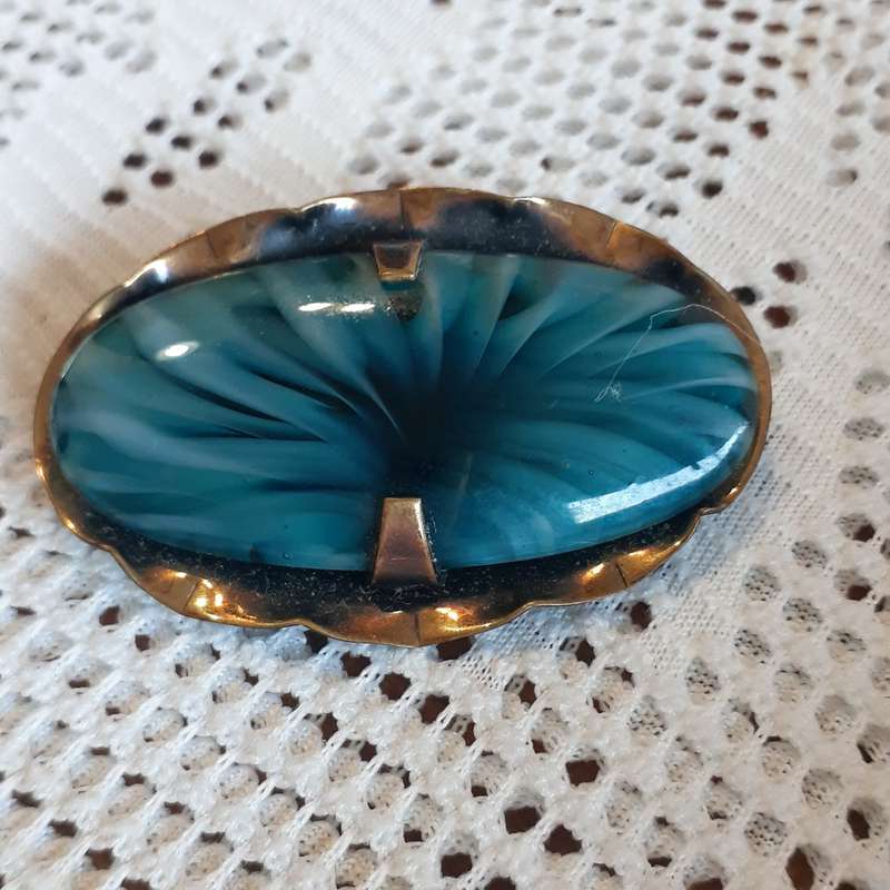 Brooch - blue glass stone on black/gilt metal base.  Italian? There are twisted ribbons in the gl...